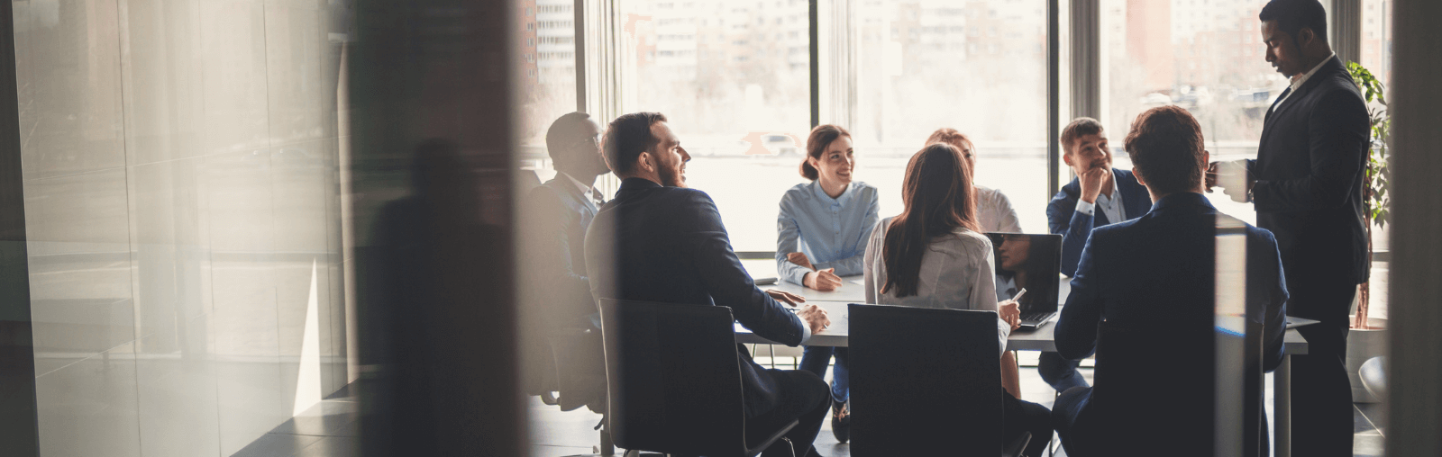 A group of people in a modern office setting having a meeting around a conference table.