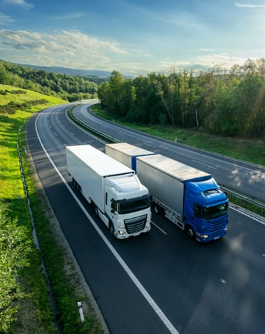 Two freight vehicles travelling down road