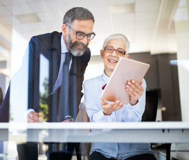 Elderly business man and woman looking at tablet together