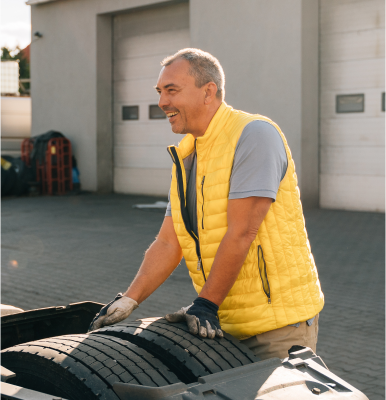 Man in yellow coat with hands on tires